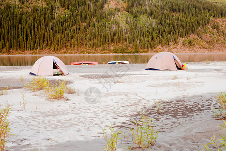 搁浅的独木舟和两个帐篷搭在加拿大育空地区育空河边的沙洲上图片