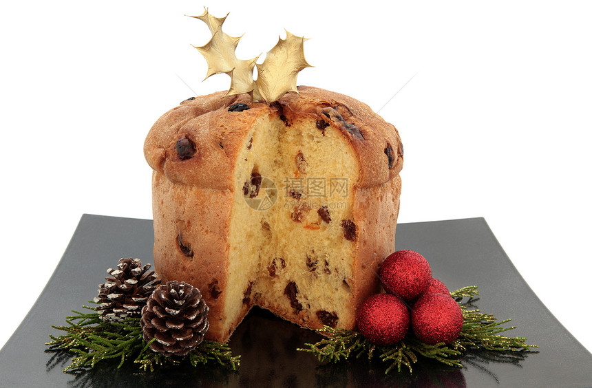 Panettone圣诞蛋糕与冬青树叶在黑色盘子上与红色小玩意集群松果和尖叶小图片