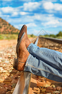 穿过火车轨道的著名牛仔靴和脚背景图片
