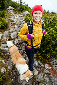 波兰Karkonosze山区妇女用阿基塔狗在山上徒步旅行图片