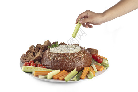 人类手握着一片蔬菜即将浸入菠菜酱中泡在奶油镍面包上图片