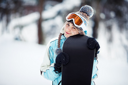年轻女士站在滑雪斜坡上拿着雪板她看着摄影机微笑复图片