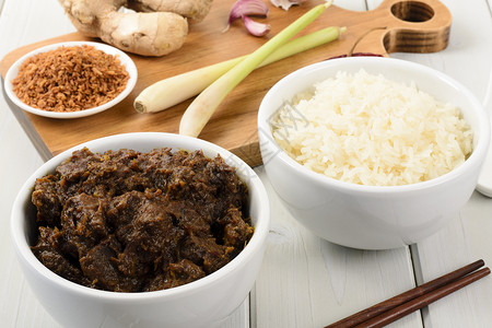 仁当牛肉和糯米饭马来西亚印度尼西亚n辛辣干牛肉炖糯米饭砧板上的主菜配料背景图片