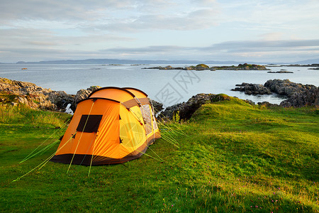晨光中岸边的橙色野营帐篷图片