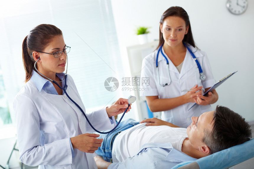 两名女医生在医院治疗期间对病人进行检查的图片