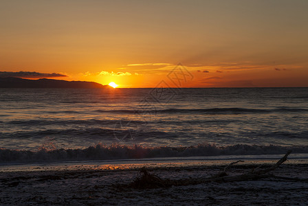 在阿拉斯加海滩上美丽的日落山浪滚进来浮木漂图片