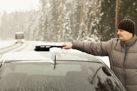 人在暴风雪中清理汽车的雪图片