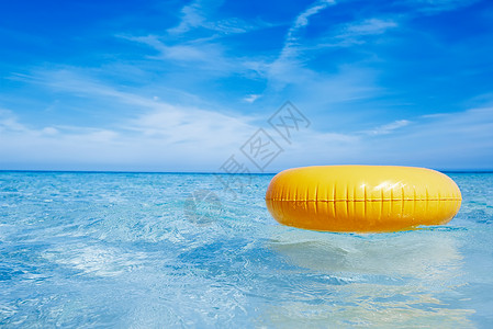 在水晶蓝色海水上漂浮的黄色环天空图片