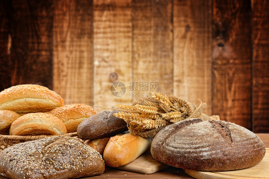 木板上的新鲜面包和小麦图片
