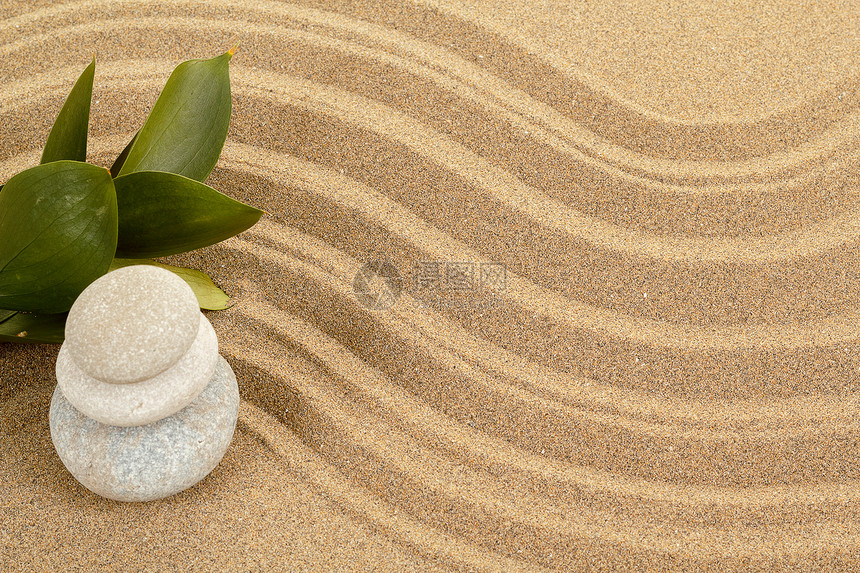 背景与平衡禅石在沙子和绿叶图片