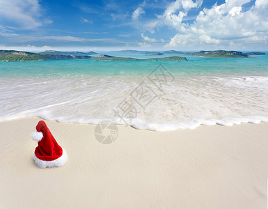 白色沙滩热带海滩上的圣诞老人帽子图片