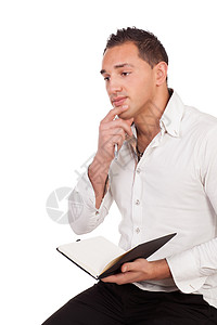 一位英俊的年轻男子坐在深思熟虑着日记或笔记本的脑海中被白色图片