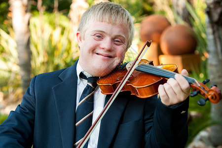 唐氏儿在户外玩小提琴的友好残疾儿背景