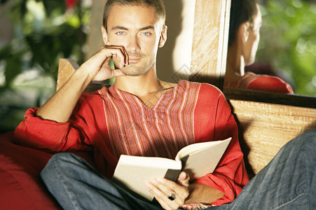 年轻人在花园沙发户外看书却坐着图片
