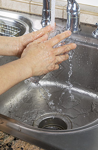女手用从厨房水龙头水槽流出的水冲洗饮水图片