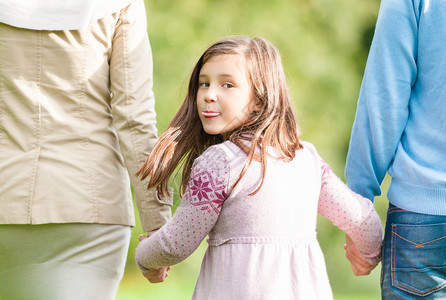 一家人在公园散步可爱的孩子牵着父母的手漂亮的女孩转过身来图片