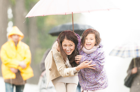快乐的母女在公园散步微笑的父母和孩子躲在伞下户外笑的女图片