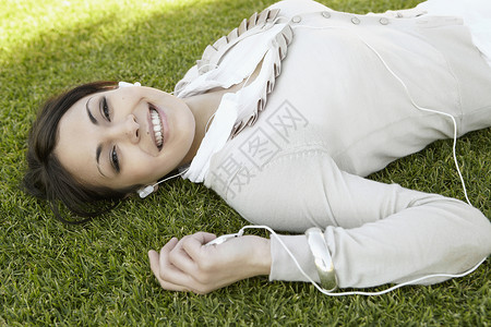 一位年轻女子在公园里躺在绿草地上图片
