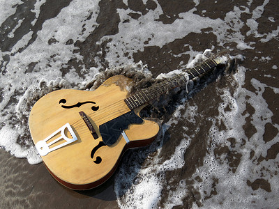 古老吉他被海浪冲走的比喻形象图片
