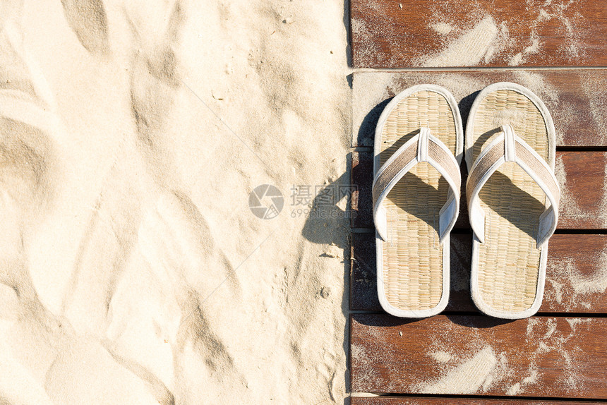 沙色和米色人字拖木板路上的一双凉鞋在阳光明媚的日子里走在沙滩上图片