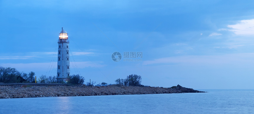 在日落期间的海滨石头和灯塔图片