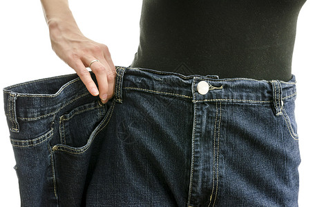 气势磅薄一个瘦的女人在减肥后腰部紧地穿着超大长的裤子背景