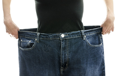 气势磅薄女人穿着她的旧牛仔裤显示她减掉了多少体背景