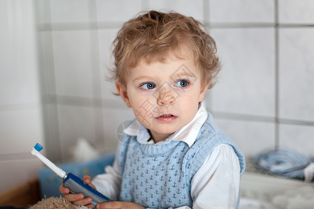 蓝眼睛和金发刷牙的可爱蹒跚学步的孩子图片