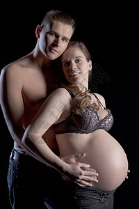 年轻人从他美丽的怀孕妻子身后温柔地抱着图片