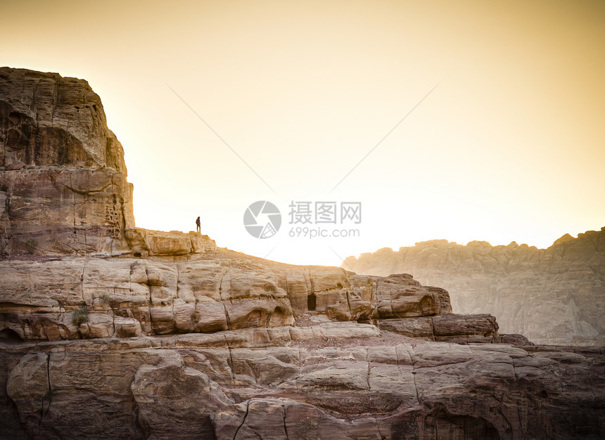 孤独的徒步旅行者在日落时站在约旦佩特拉的岩石上图片