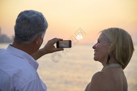 旅行和活跃的老年男女在海上观海和用智能手机拍照图片