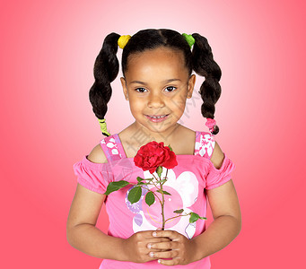带着红玫瑰微笑的小女孩在粉红背景上图片