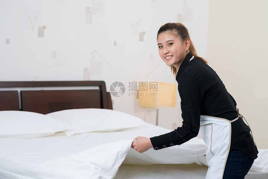 在酒店房间整理床铺的女佣图片