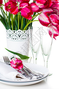 以白色花瓶和古年葡萄酒杯中的明粉红色郁金香的花束装在节日桌布图片
