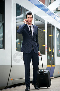 旅行商人在地铁站用背景列车通电话的图片
