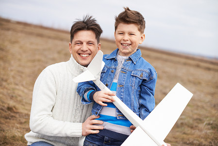 喜悦的男孩与玩具飞机和他父亲图片