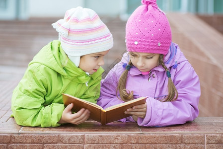 两个穿大衣的漂亮小女孩在读橘子书图片