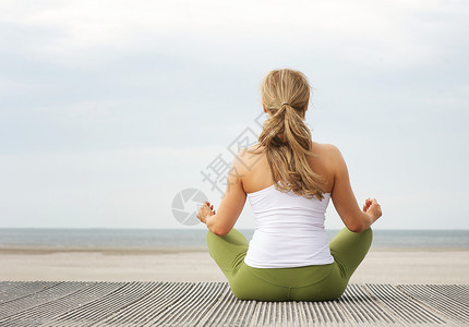 坐在沙滩的瑜伽姿势上一位年轻女子图片
