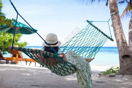 戴帽子的女人躺在吊床上在海滩图片