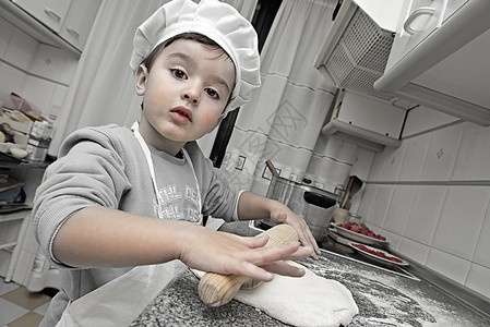 孩子打扮成厨师在厨房工作图片