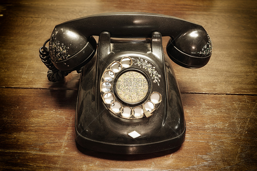 旧木板上带旋转拨号的旧电话图片