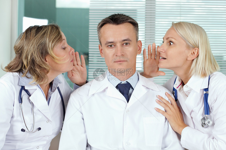 男临床医生在两个流言蜚语的女之间平图片