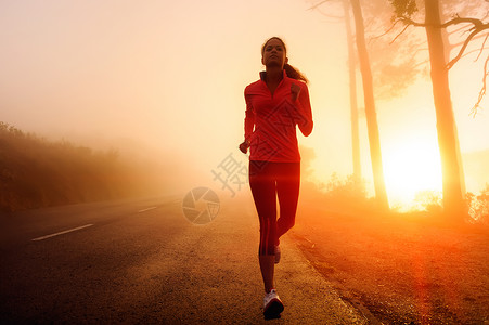 健康的跑步者女人清晨日出锻炼在雾蒙的山路锻炼慢跑透过薄雾的阳光为这些健身图像带来背景图片