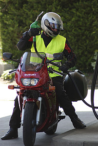 摩托车手为他的红色摩托车加油图片