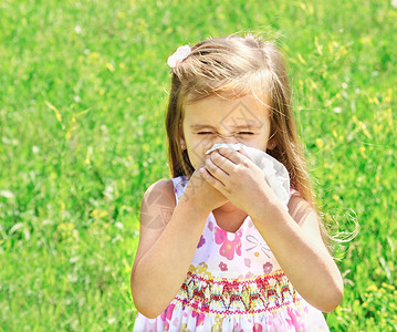小女孩因绿色草地过敏而擤鼻涕图片