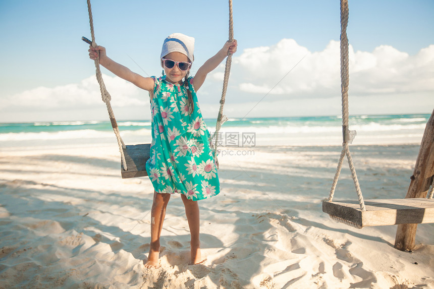 穿着洋装和墨镜的可爱小女孩在白色沙滩上的加勒图片