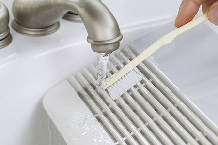 女手用牙刷扫洗手间风扇在浴室水槽中喷口罩贴图片