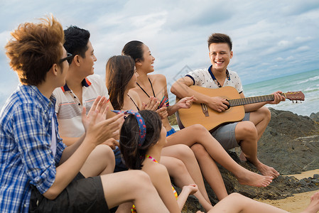 朋友团队在海岸和弹吉他的画面在图片