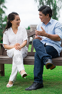 坐在长椅上和在外面交谈的成熟夫妇的垂直图片