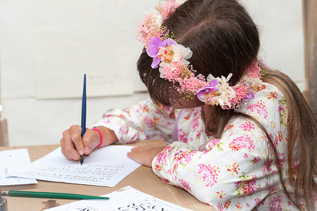 希伯来女孩坐在白色背景上用钢笔写字图片